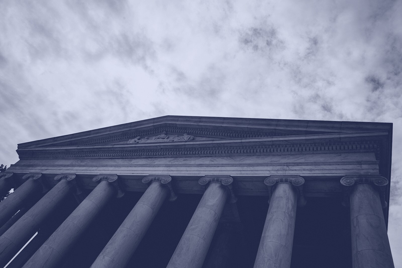Classical building facade with columns against cloudy sky