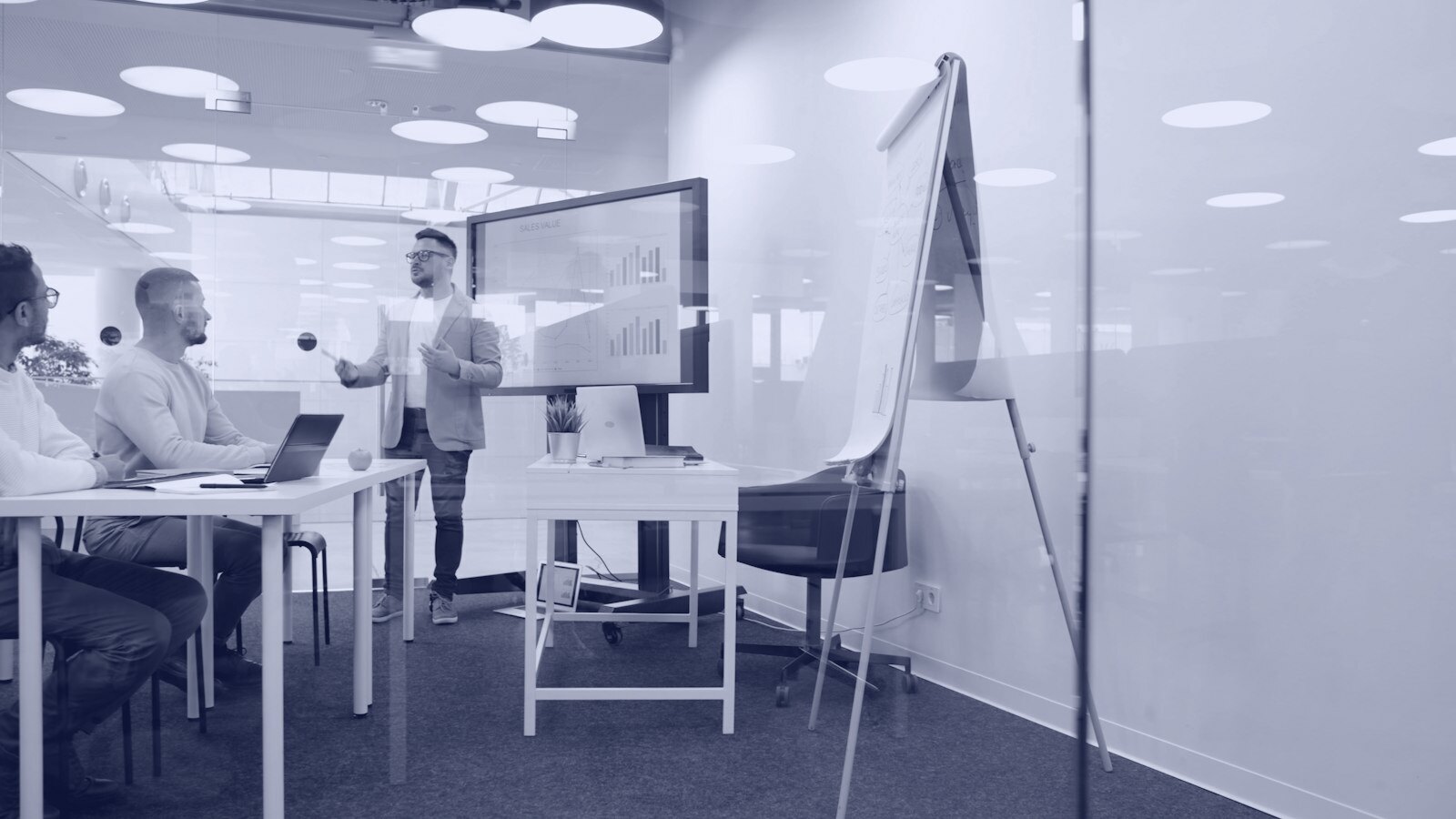 Man presenting to colleagues in a modern office meeting