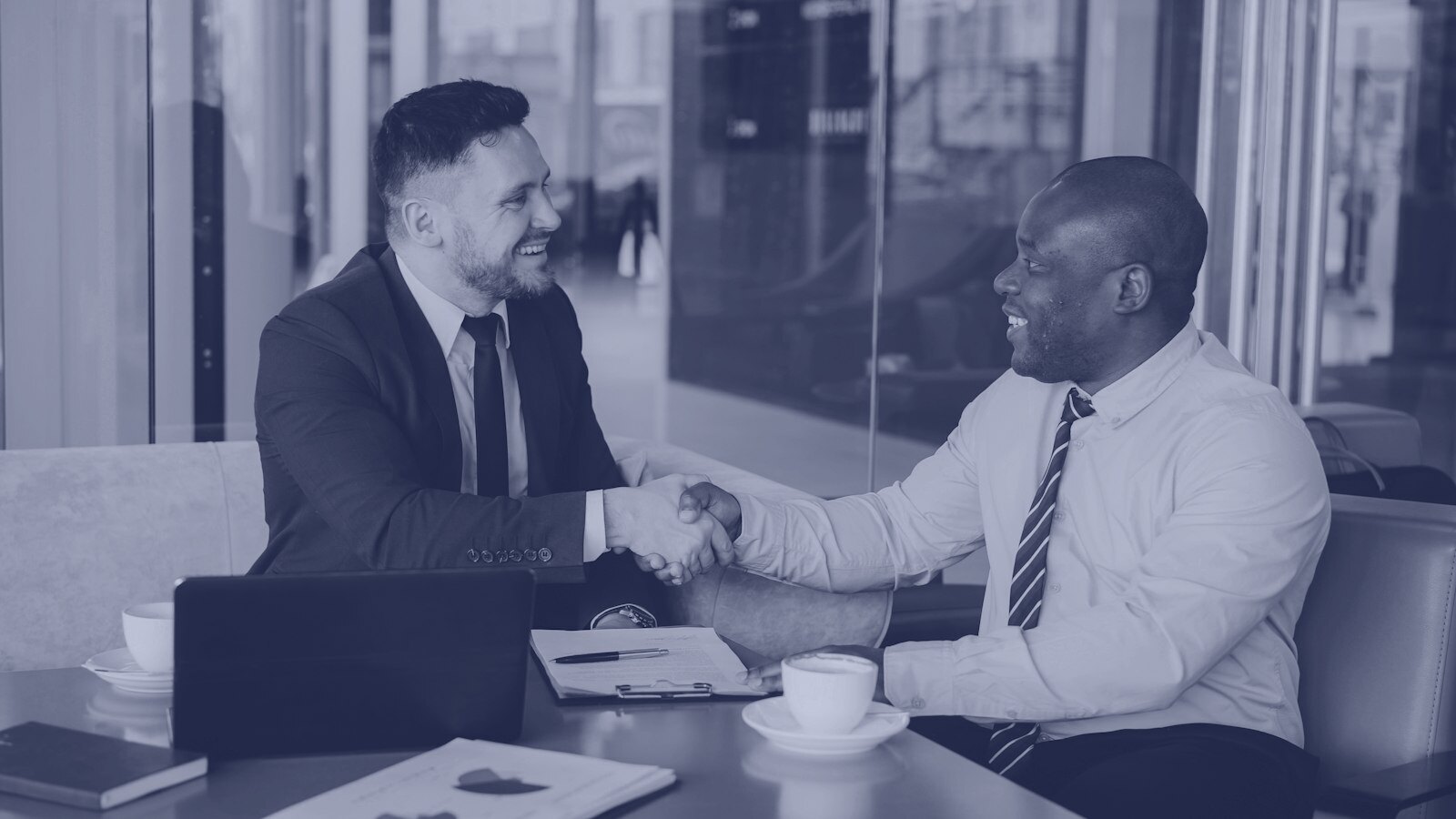 Two businessmen shaking hands across a table