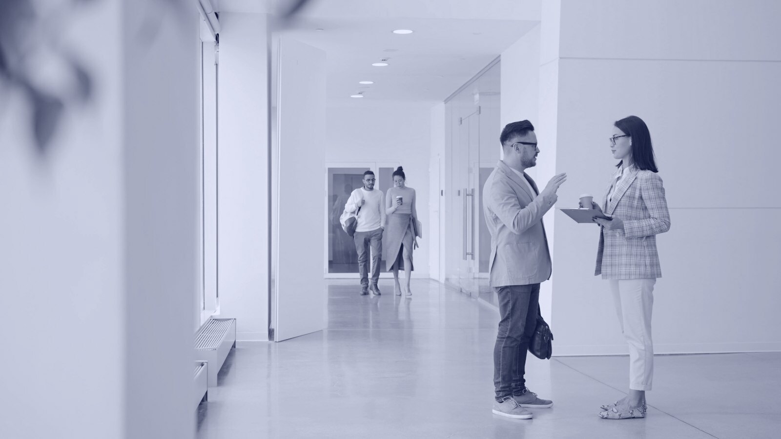 Two people talking in a modern office hallway