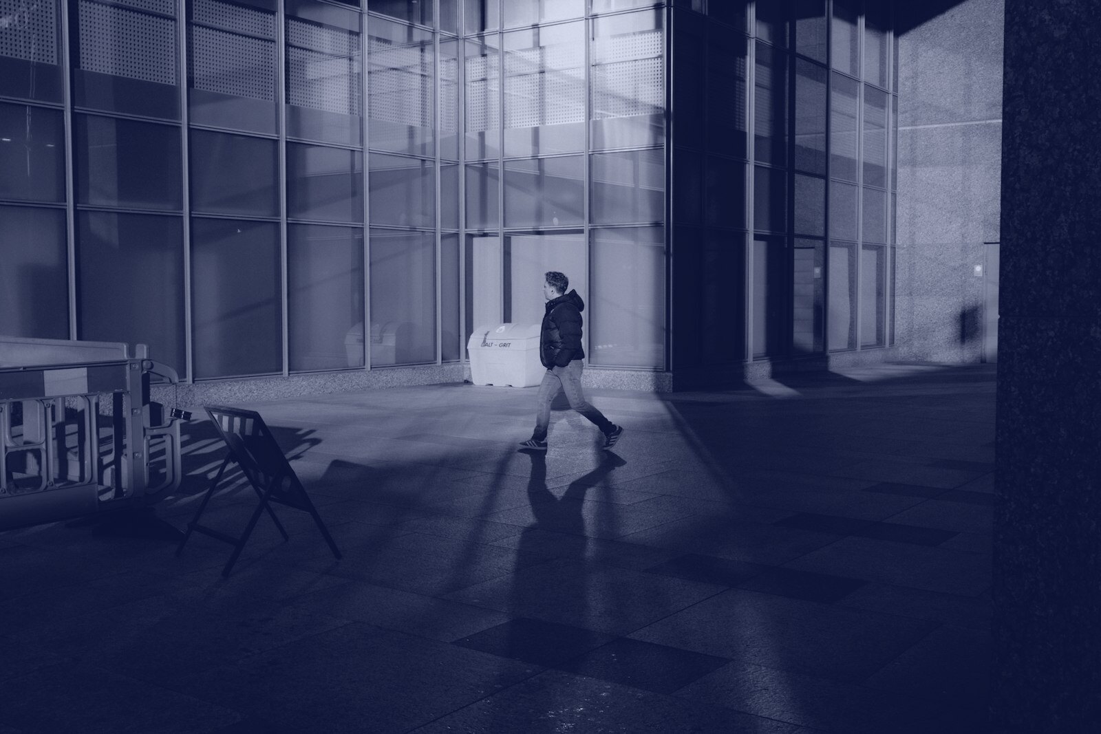 A man walking down a street next to a tall building