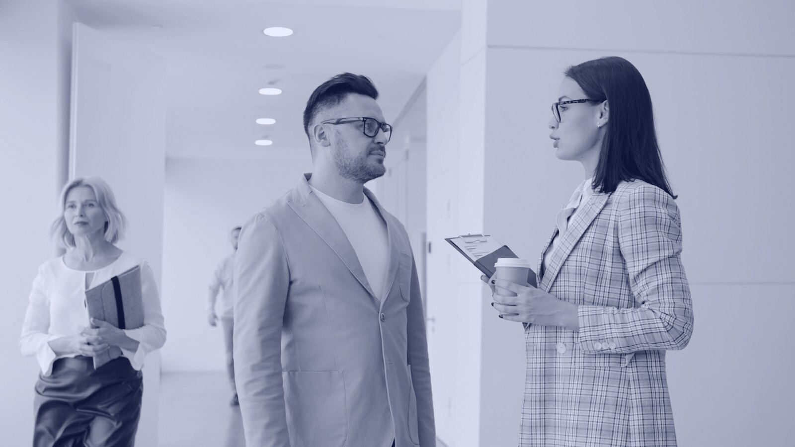 Two colleagues talking in a modern office hallway